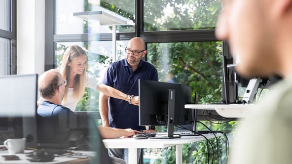 IT-Team im Gespräch mit Blick auf den Bildschirm