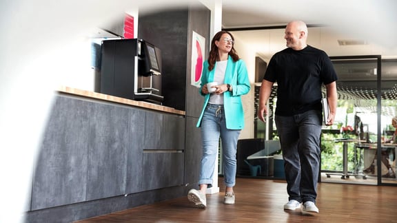 Mitarbeitende tauschen sich an der Kaffeemaschine aus