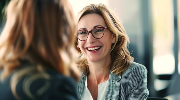 Freundliches Bewerbungsgespräch zwischen zwei Frauen – Symbol für faire Auswahlverfahren im öffentlichen Dienst.